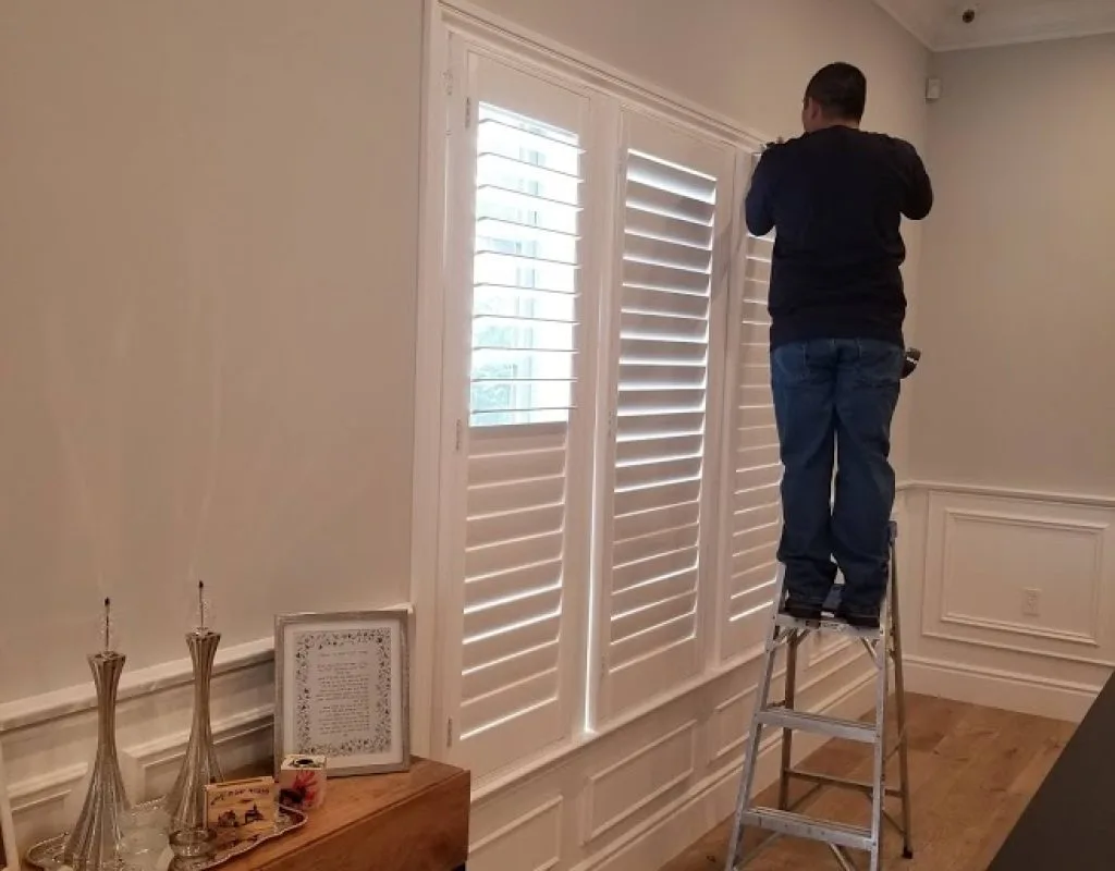 Shutters installation technician adjusting plantation shutters