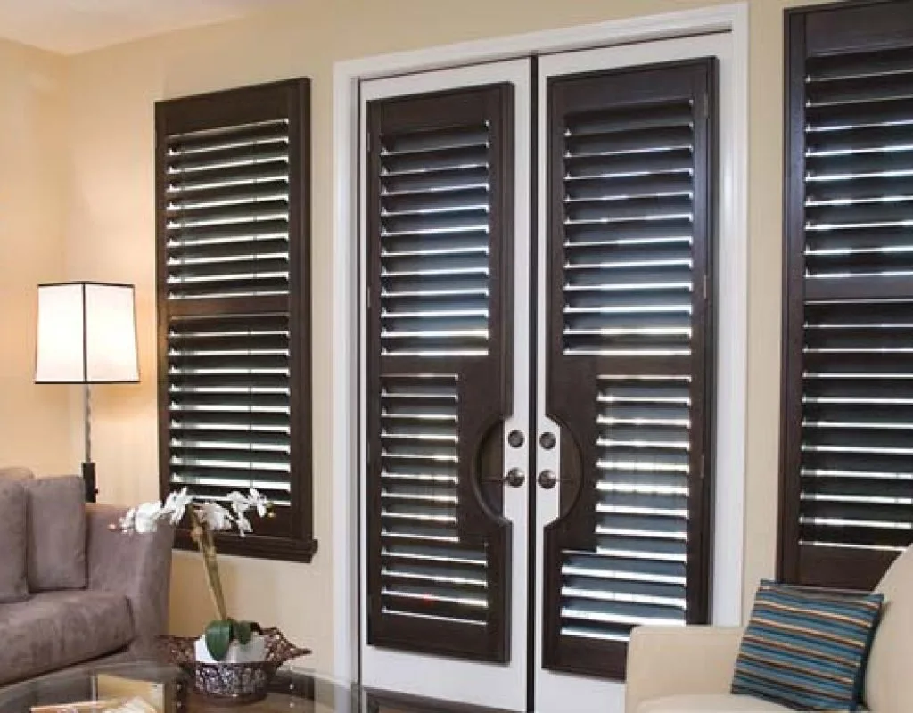 Custom wood shutters on living room windows with sunlight